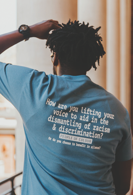 A man poses with his People of Color tshirt