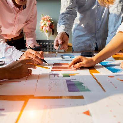 people standing around a table analyzing a chart