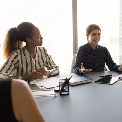a group of women sitting at a table as one speaks