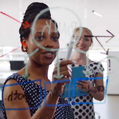 two women looking over a chart drawn on a a pane of glass in front of the camera