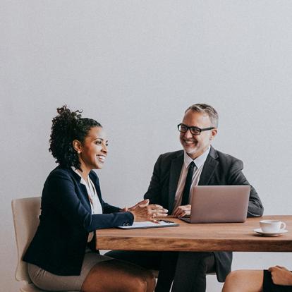 two people in suits sitting at a table having a discussion