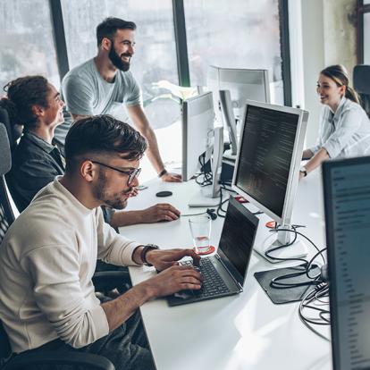 a group of people working on computers around a table