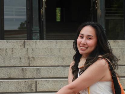 MBA College of Business graduate Hazel Segismar-Coles sits on steps with diploma