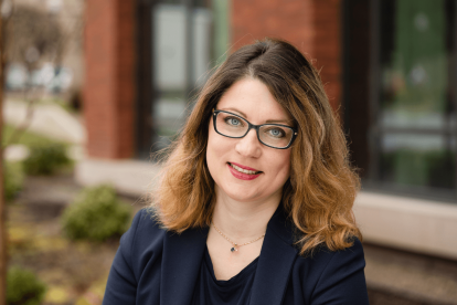 Photo of Violetta Gerasymenko in front of Austin Hall. Gerasymenko is wearing a dark blue shirt and is wearing glasses.