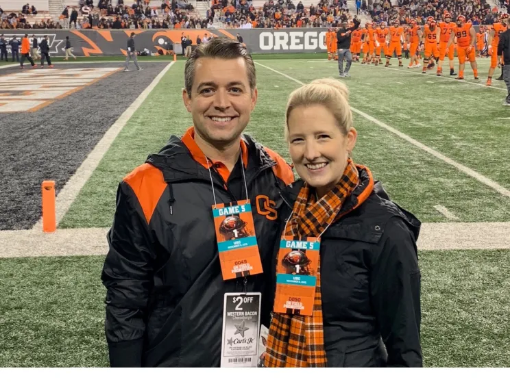 Scott Christianson with his wife at a football game. Both are wearing Beaver gear.